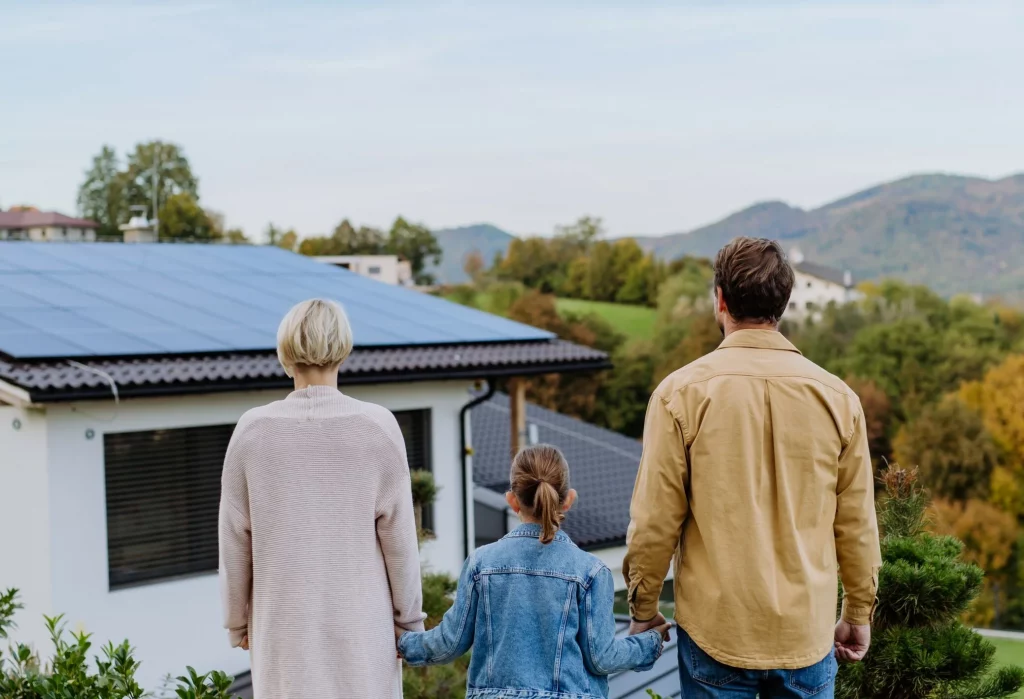 Familie steht vor Haus mit Solaranlage